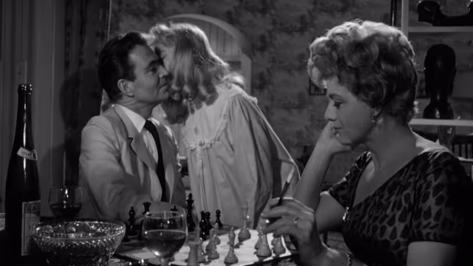Humbert Humbert (James Mason) kisses Lolita (Sue Lyon) as Charlotte watches at dinner