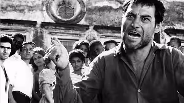 Zé do Burro (Leonardo Villar) gestures as he speaks to a crowd outside the church