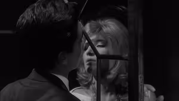 Vittoria (Monica Vitti) faces a man through the bars of a doorway