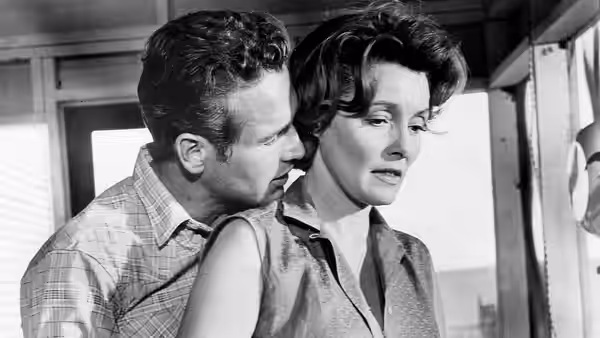 Hud Bannon (Paul Newman) leans close to Alma Brown (Patricia Neal) indoors