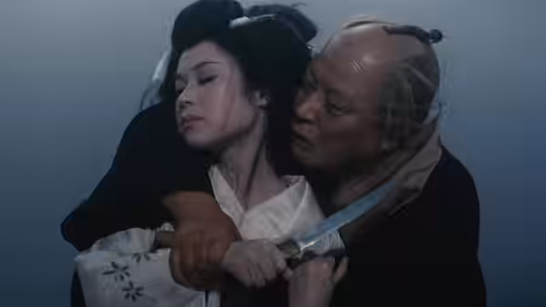 An older man restrains a woman and presses a knife against her