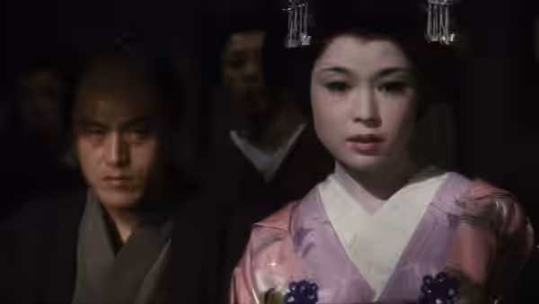 A woman in a pink kimono stands before several shadowed men