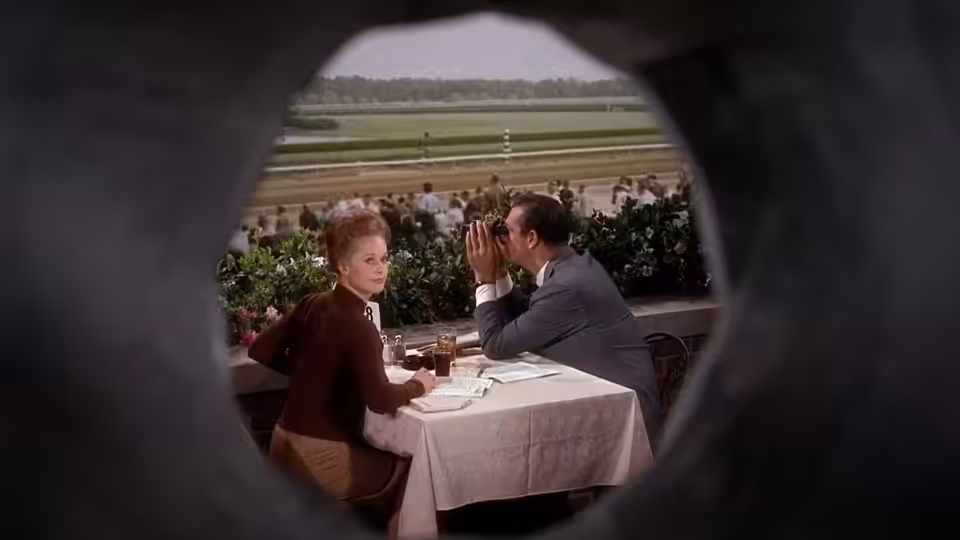 Marnie Edgar (Tippi Hedren) sits across from Mark Rutland (Sean Connery) at a racetrack table