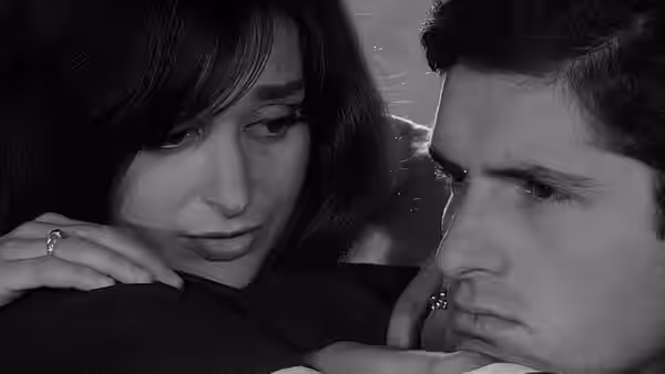 A woman and a man lean close together, both looking down