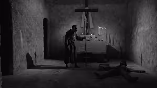 Sebastião (Lídio Silva) stands beside an altar and crucifix as a man lies on the floor