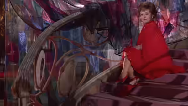 Giulietta (Giulietta Masina) in a red dress sits on a curving staircase