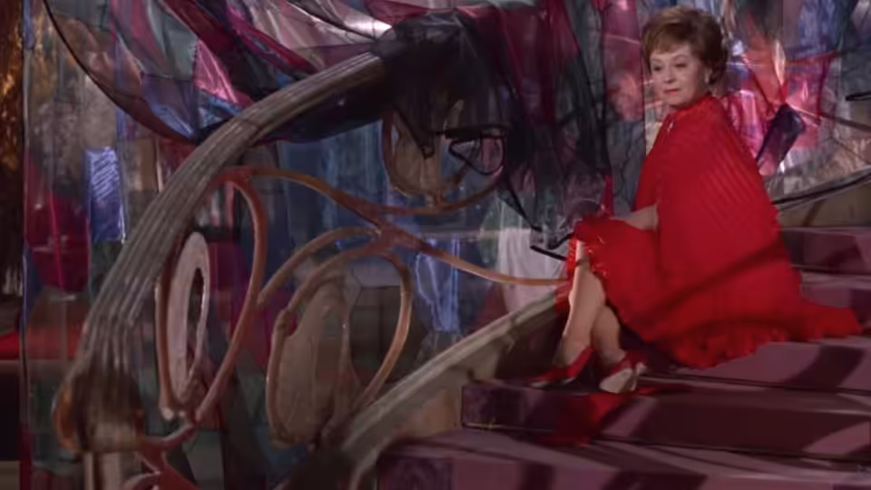 Giulietta (Giulietta Masina) in a red dress sits on a curving staircase