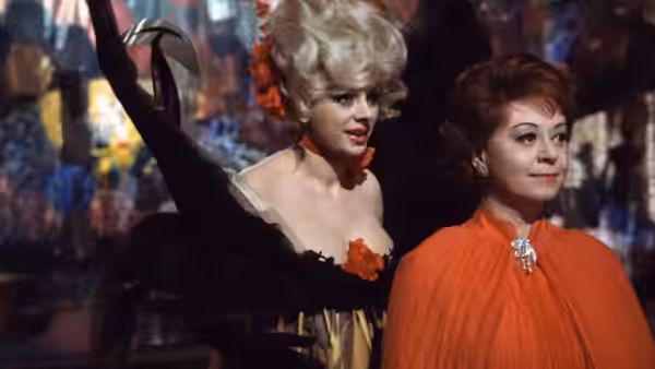 Giulietta (Giulietta Masina) in an orange cape stands beside a woman in a black dress