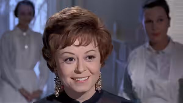 Giulietta (Giulietta Masina) smiles between two attendants in a bright room