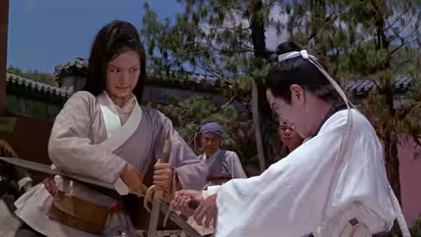 A woman and a man handle a sword in a courtyard as others watch
