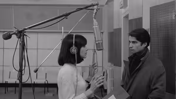 Madeleine Zimmer (Chantal Goya), wearing headphones, speaks with Paul (Jean-Pierre Léaud) in a recording studio