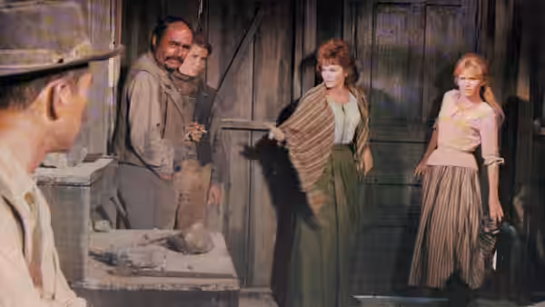 A group of travelers gathers inside a dim wooden building