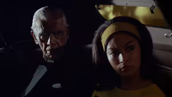 Byron Orlok (Boris Karloff) rides in a car beside Jenny (Nancy Hsueh)