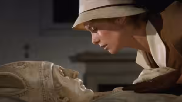 Tristana (Catherine Deneuve) leans over a reclining stone figure