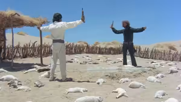 Two men face each other with arms raised among scattered bodies in the desert