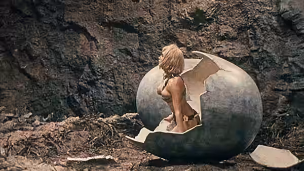 A blonde woman rises from a broken egg in a rocky cave
