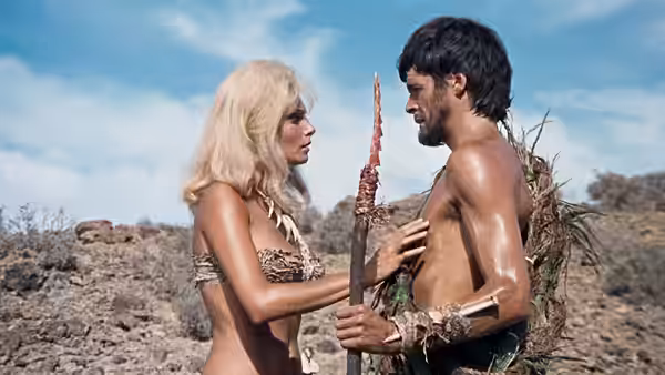 Sanna (Victoria Vetri) faces Tara (Robin Hawdon), holding a spear in the rocky landscape