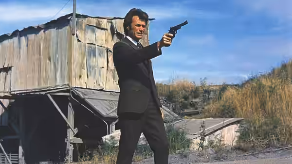 Harry (Clint Eastwood) aims a revolver beside a wooden industrial building