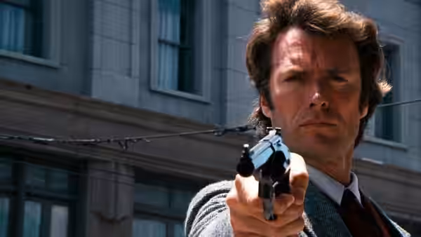 Harry (Clint Eastwood) aiming his revolver in front of a city building