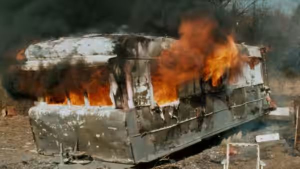 A trailer burns fiercely in an open area