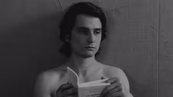 Alexandre (Jean-Pierre Léaud) reads a book while holding it open