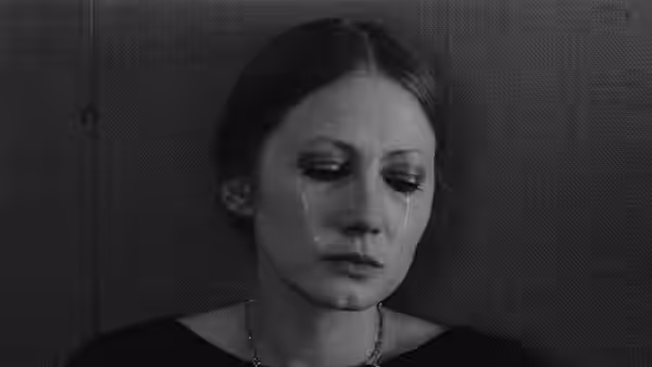 A woman looks down with tears on her cheeks
