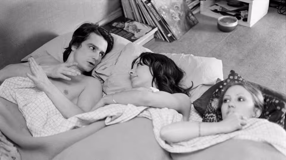 Alexandre (Jean-Pierre Léaud) lies in bed beside a woman and a child under the covers