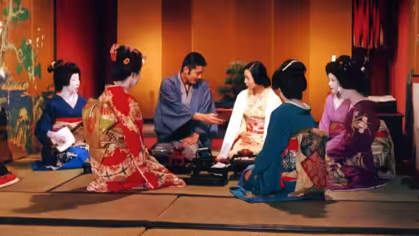 Kichizo Ishida (Tatsuya Fuji) sits among geishas in a traditional Japanese room