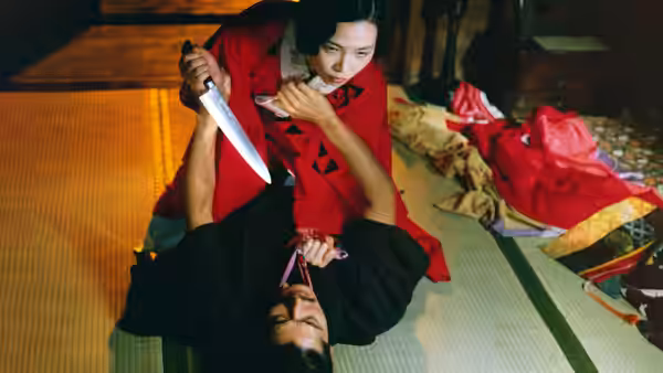 Sada Abe (Eiko Matsuda) restrains Kichizo Ishida while holding a knife above him