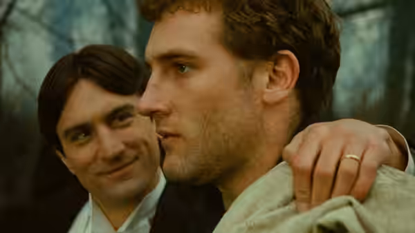 A smiling man drapes an arm over a tense young man outdoors