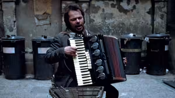 Bruno Stroszek (Bruno Schleinstein) plays an accordion in a courtyard lined with rubbish bins