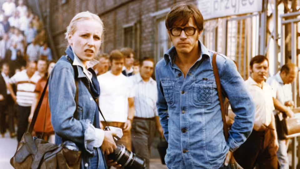 Agnieszka (Krystyna Janda) and a bespectacled man stand among a crowd outside a building