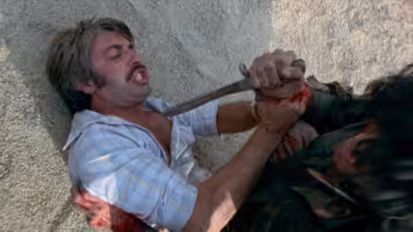 Doug Wood (Martin Speer) struggles on the ground with an attacker holding a knife