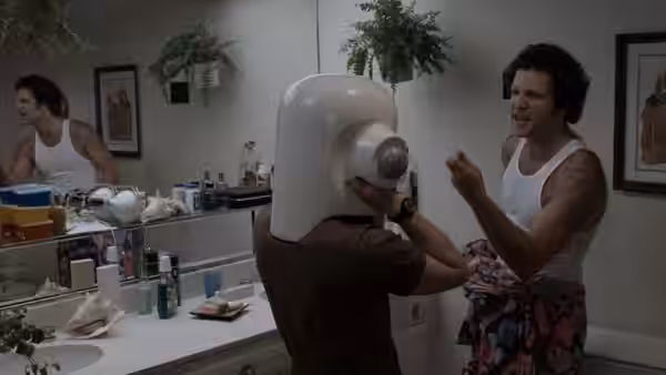 Albert Brooks (Albert Brooks) gestures beside a man wearing a large robot helmet in a bathroom