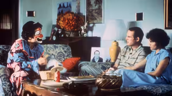 Albert Brooks (Albert Brooks), dressed as a clown, talks with Warren Yeager (Charles Grodin) and Jeannette Yeager (Frances Lee McCain) on their couch