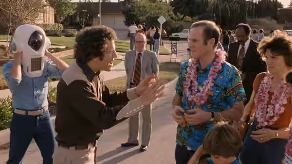 Albert Brooks (Albert Brooks) gestures toward Warren Yeager (Charles Grodin), wearing leis outside his home