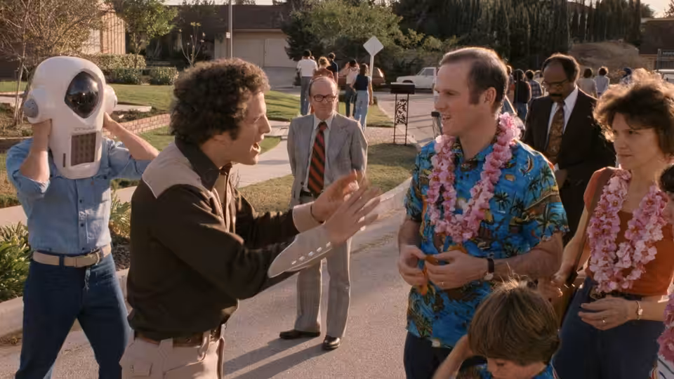 Albert Brooks (Albert Brooks) gestures toward Warren Yeager (Charles Grodin), wearing leis outside his home