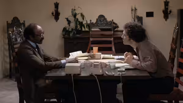 Albert Brooks (Albert Brooks) leans across a dining table toward a suited man
