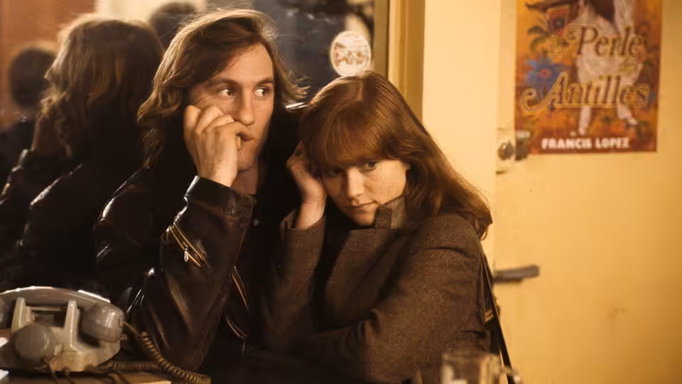 Loulou (Gérard Depardieu) and Nelly (Isabelle Huppert) sit close together at a counter
