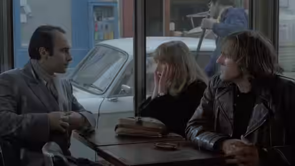 André (Guy Marchand) sits across from Nelly (Isabelle Huppert) and Loulou (Gérard Depardieu) in a café