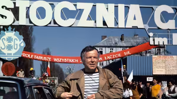 Winkel (Marian Opania) stands outside the Gdańsk Shipyard entrance amid workers and banners