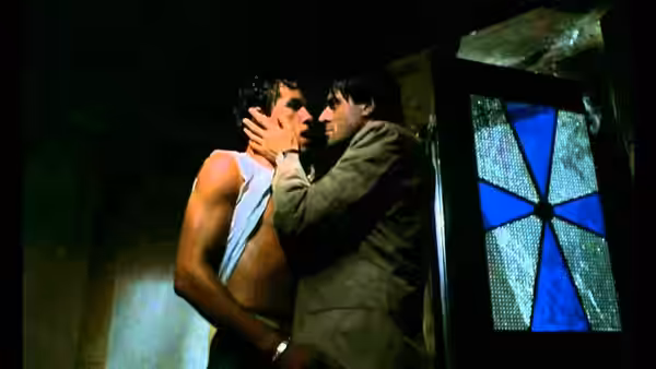Two men kiss beside a stained-glass window, one gripping the other's face