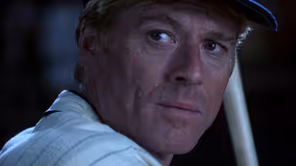 Roy Hobbs (Robert Redford) looks over his shoulder in a baseball cap