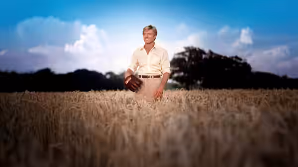 Roy Hobbs (Robert Redford) stands in a wheat field holding a baseball glove