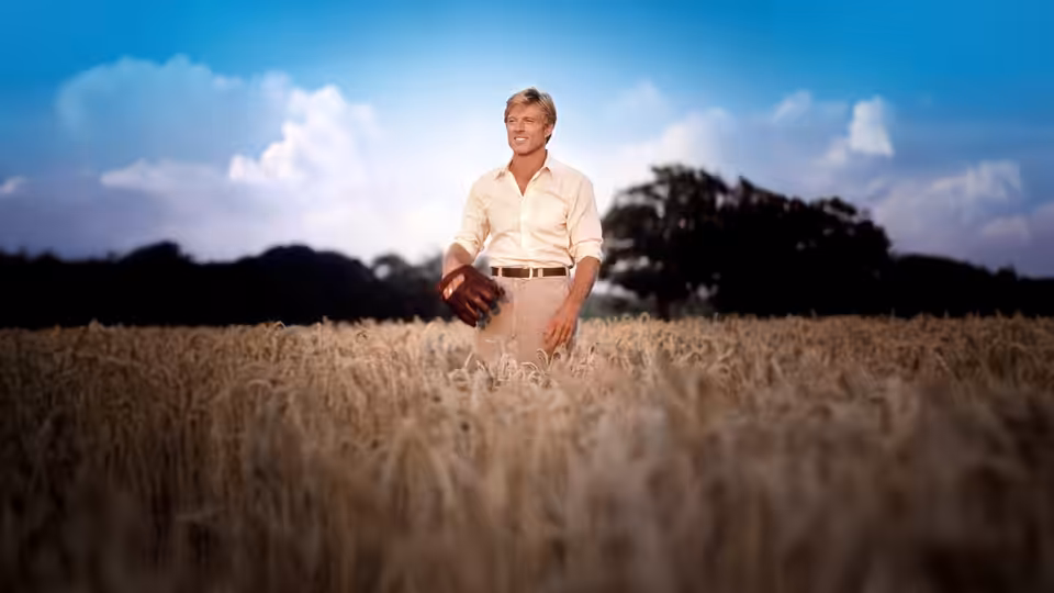Roy Hobbs (Robert Redford) stands in a wheat field holding a baseball glove