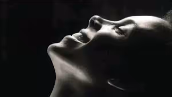 A woman reclines in profile with her face turned upward