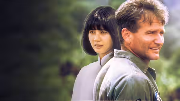 Adrian Cronauer (Robin Williams) stands beside Trinh (Chintara Sukapatana) outdoors