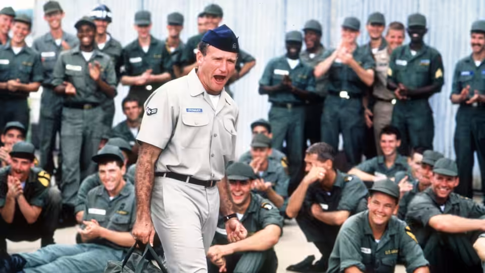 Adrian Cronauer (Robin Williams) entertains laughing soldiers outdoors