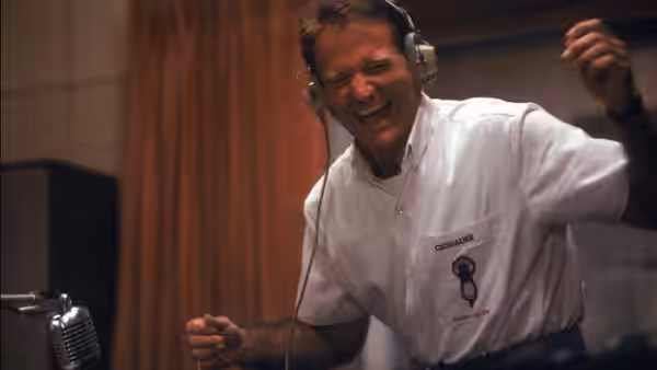 Adrian Cronauer (Robin Williams) laughs at a microphone in the radio studio