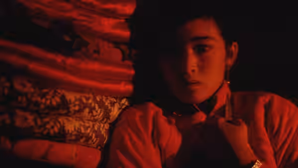 Jiu'er (Gong Li) clutches her clothes beside patterned bedding in a dim room
